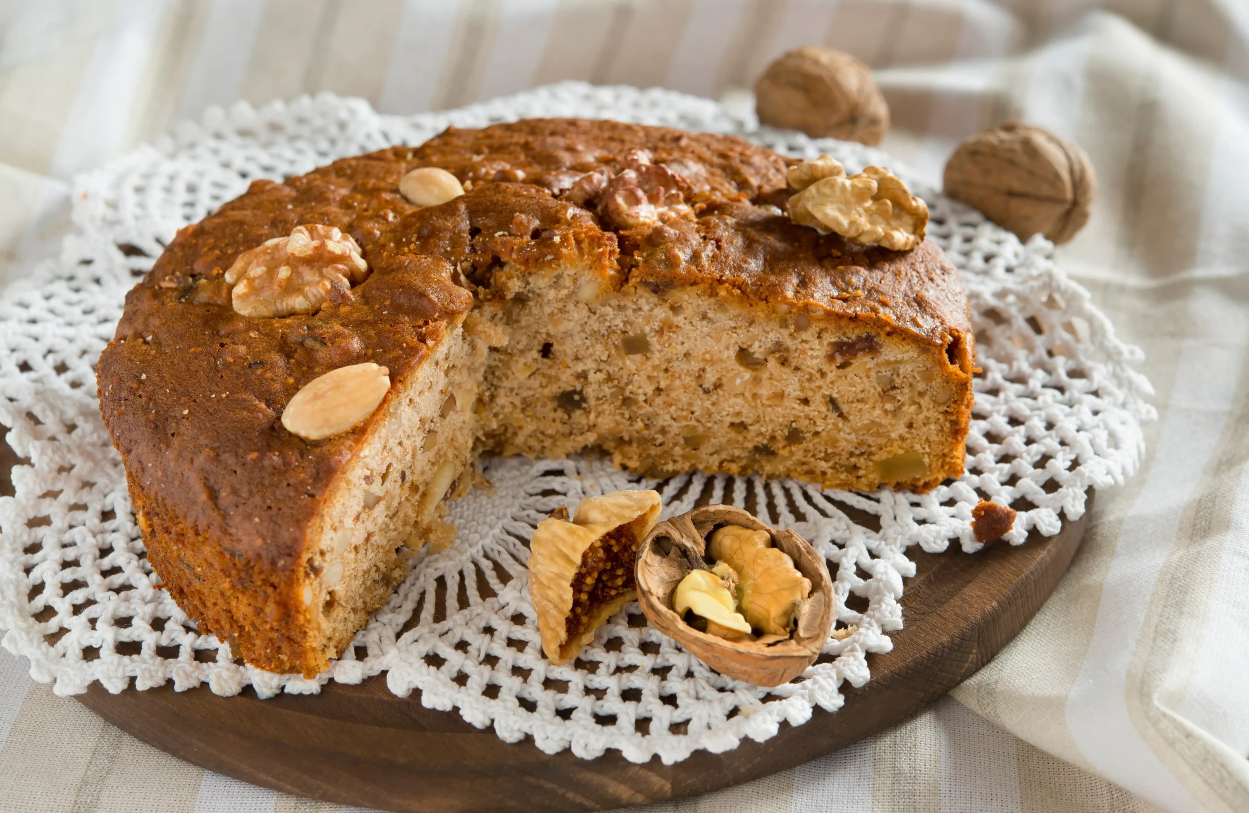 Torta alle noci decorata con mandorle su un vassoio di legno.